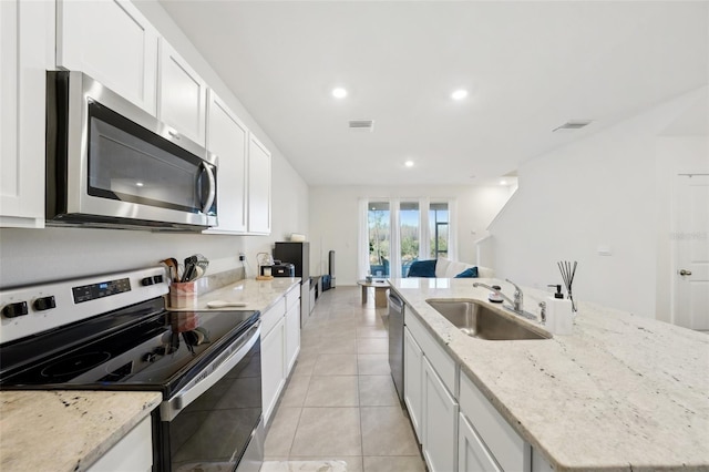 kitchen featuring sink, white cabinetry, light stone counters, stainless steel appliances, and a kitchen island with sink