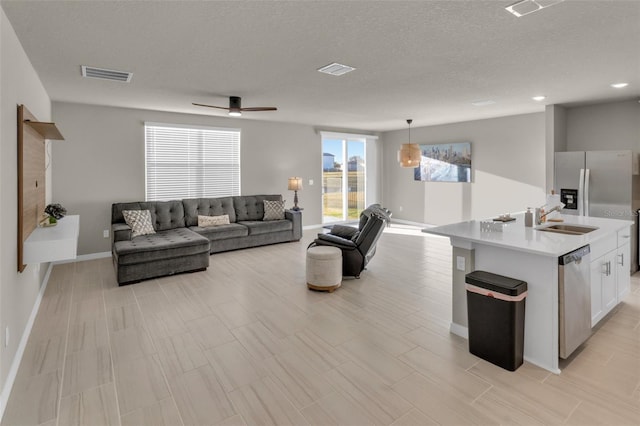 living room featuring ceiling fan, sink, and a textured ceiling