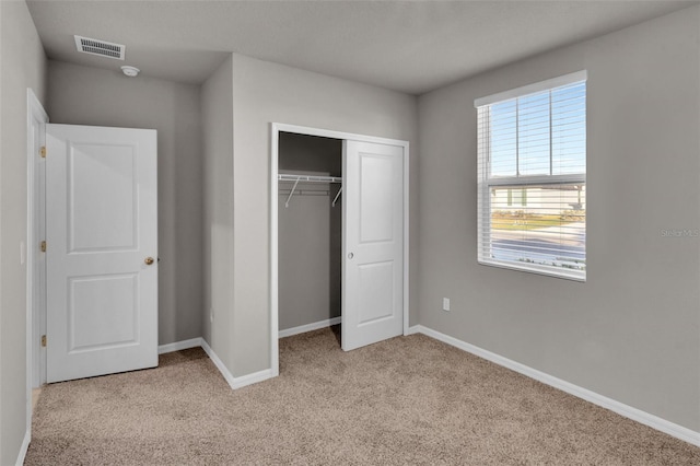 unfurnished bedroom featuring light carpet and a closet