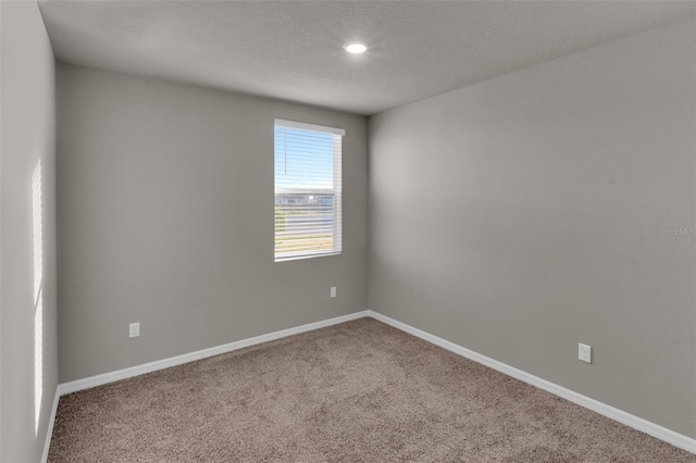 carpeted empty room featuring a textured ceiling