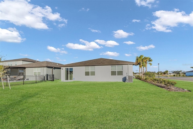 rear view of property with a yard and central air condition unit