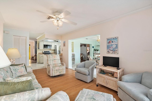 living room featuring ceiling fan, ornamental molding, and light wood-type flooring