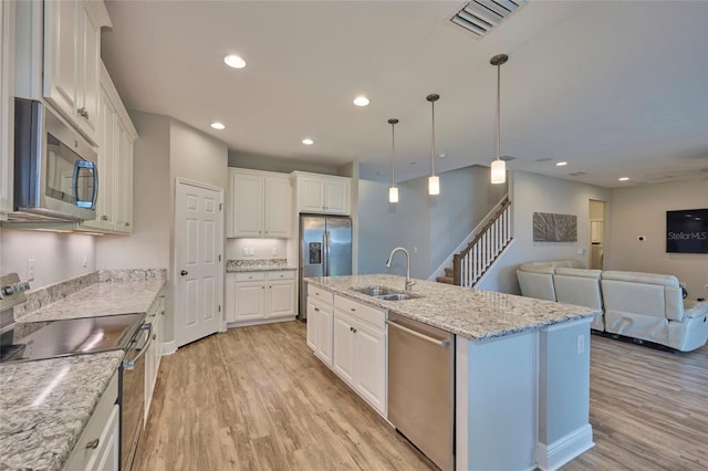 kitchen featuring stainless steel appliances, sink, an island with sink, and white cabinets