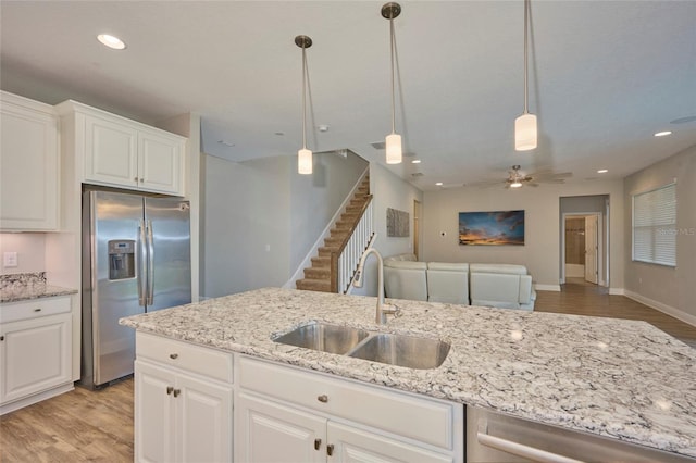 kitchen with sink, white cabinetry, pendant lighting, stainless steel appliances, and light hardwood / wood-style floors