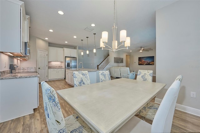 dining room with sink, ceiling fan with notable chandelier, and light hardwood / wood-style floors