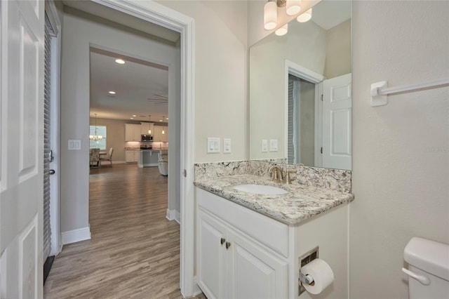 bathroom with an inviting chandelier, vanity, toilet, and hardwood / wood-style flooring