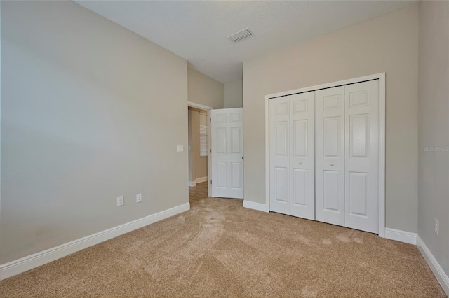 unfurnished bedroom with a closet and light colored carpet