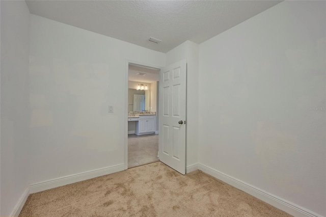 unfurnished room with light colored carpet and a textured ceiling