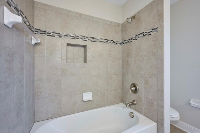 bathroom featuring tiled shower / bath and toilet