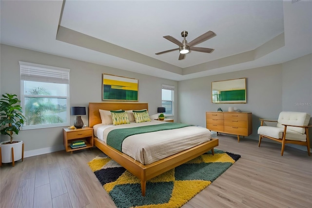 bedroom with a raised ceiling, hardwood / wood-style flooring, and ceiling fan