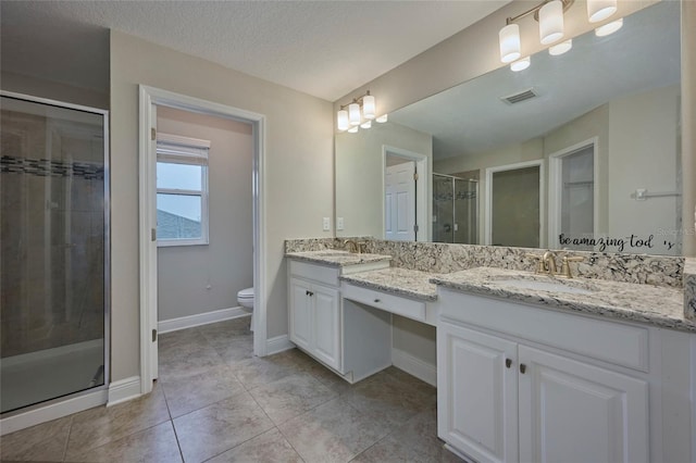 bathroom featuring vanity, a textured ceiling, a shower with shower door, tile patterned floors, and toilet