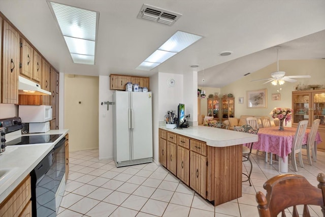 kitchen featuring light tile patterned floors, white appliances, a breakfast bar, vaulted ceiling, and kitchen peninsula