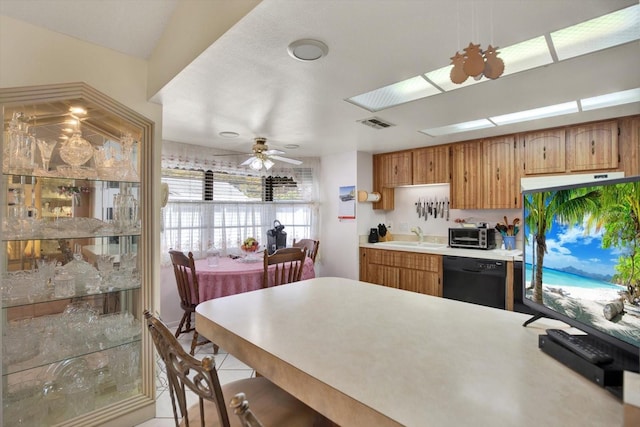 kitchen featuring sink, light tile patterned floors, ceiling fan, a skylight, and black dishwasher