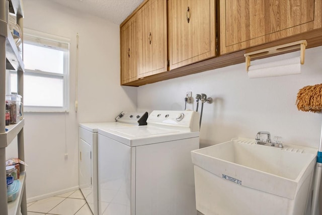 washroom featuring light tile patterned flooring, washing machine and clothes dryer, sink, cabinets, and a textured ceiling