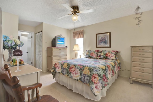 bedroom with ceiling fan, light colored carpet, a closet, and a textured ceiling