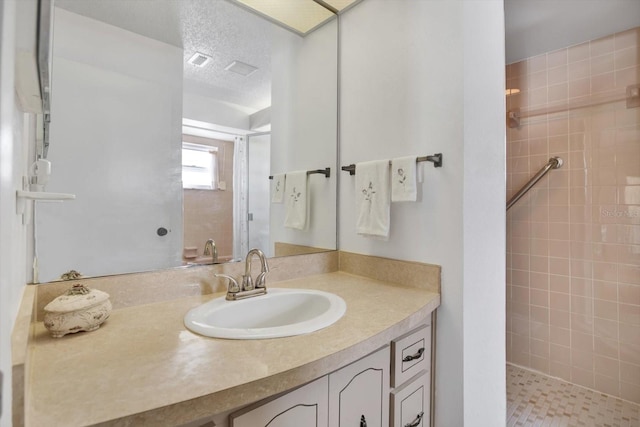 bathroom with vanity, a textured ceiling, and tiled shower