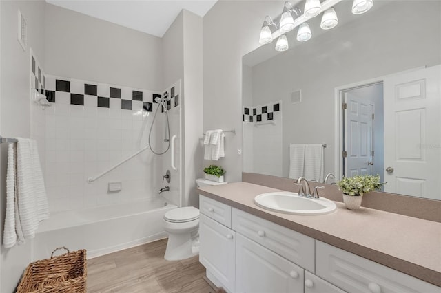 full bathroom with vanity, tiled shower / bath combo, wood-type flooring, and toilet