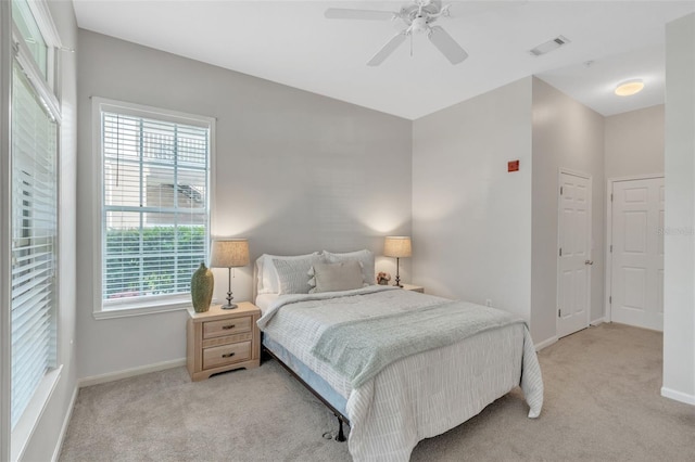 carpeted bedroom featuring multiple windows and ceiling fan