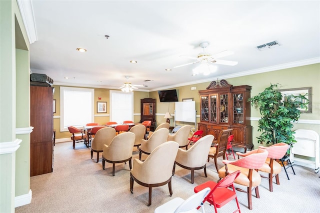 carpeted dining space featuring crown molding and ceiling fan