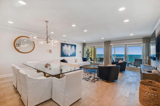 dining room featuring light hardwood / wood-style flooring, ornamental molding, and a water view