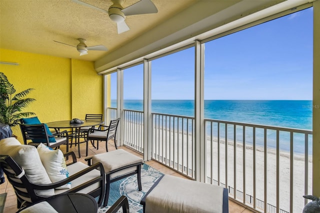 sunroom featuring a water view, a beach view, and ceiling fan