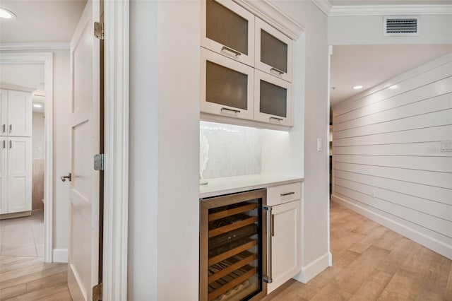 bar with white cabinetry, beverage cooler, and light hardwood / wood-style flooring