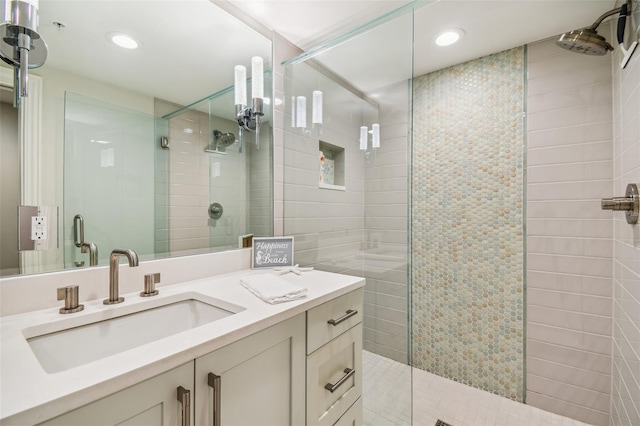 bathroom featuring a shower with door and vanity