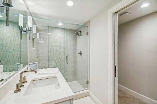 bathroom featuring hardwood / wood-style flooring, vanity, and a shower with shower door