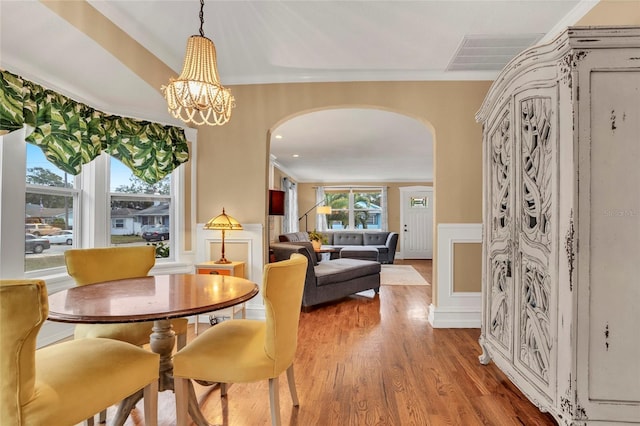 dining area with ornamental molding, hardwood / wood-style floors, and a notable chandelier