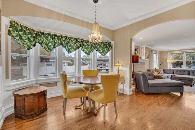 dining area with crown molding, a chandelier, and light wood-type flooring