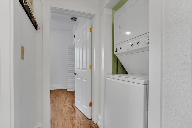 laundry area with stacked washer and dryer and light hardwood / wood-style flooring