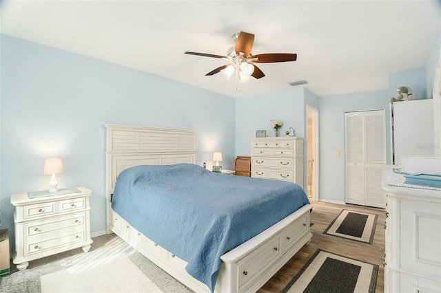 bedroom with wood-type flooring, ceiling fan, and a closet