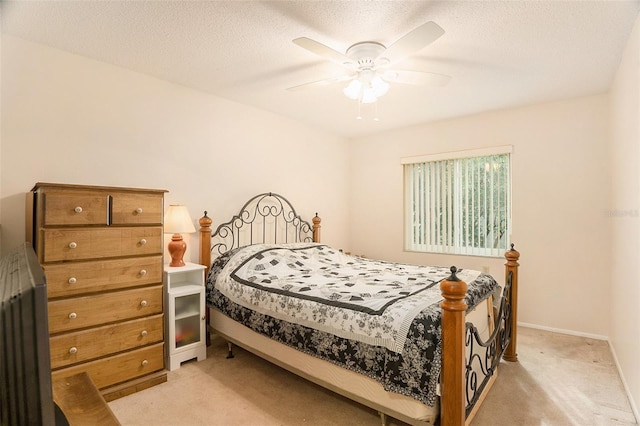 carpeted bedroom featuring ceiling fan and a textured ceiling