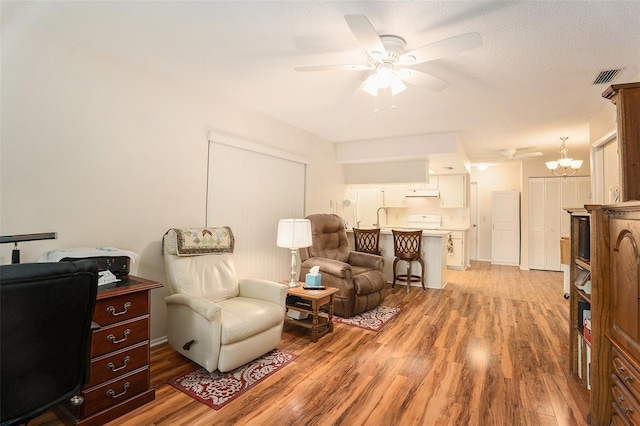 living area with sink, ceiling fan with notable chandelier, a textured ceiling, and light hardwood / wood-style floors