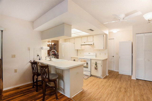 kitchen featuring ceiling fan with notable chandelier, sink, light hardwood / wood-style floors, kitchen peninsula, and white appliances