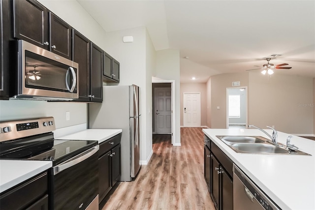 kitchen featuring appliances with stainless steel finishes, lofted ceiling, sink, ceiling fan, and light hardwood / wood-style floors