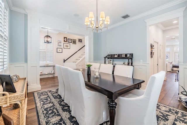 dining space with hardwood / wood-style floors, crown molding, and a chandelier