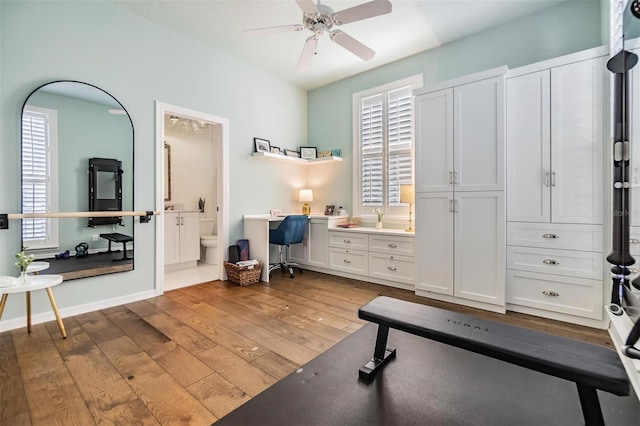 exercise area featuring hardwood / wood-style floors, built in desk, and ceiling fan