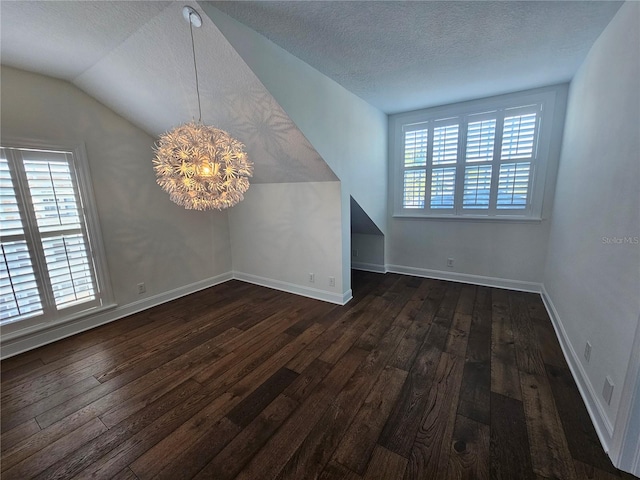 interior space with dark wood-type flooring, a chandelier, a textured ceiling, and vaulted ceiling