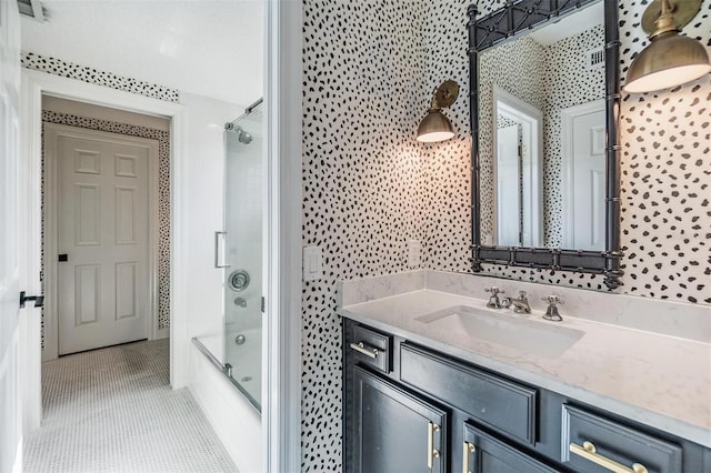 bathroom featuring enclosed tub / shower combo, vanity, tile patterned flooring, and tile walls