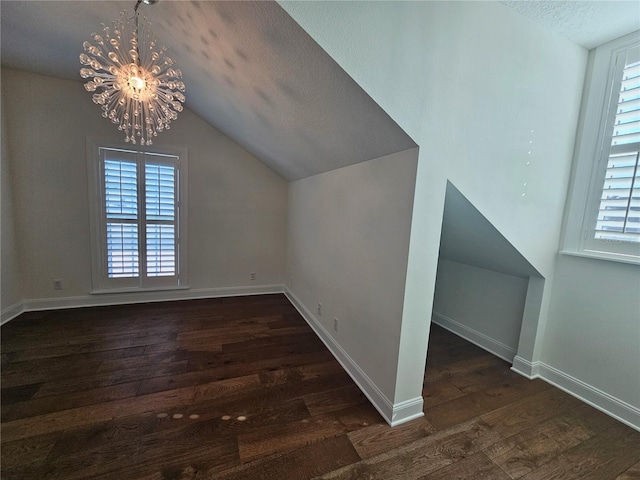 additional living space featuring dark hardwood / wood-style flooring, vaulted ceiling, a textured ceiling, and an inviting chandelier