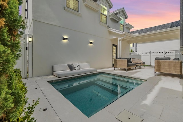 pool at dusk featuring an outdoor living space and a patio