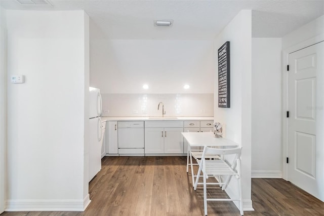 kitchen featuring dark hardwood / wood-style floors, tasteful backsplash, sink, white cabinets, and white appliances