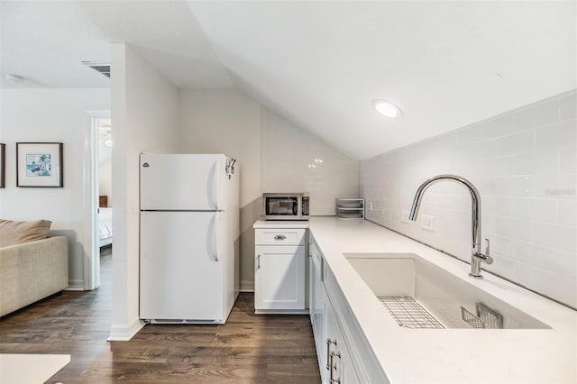 kitchen featuring vaulted ceiling, white cabinetry, white fridge, and sink