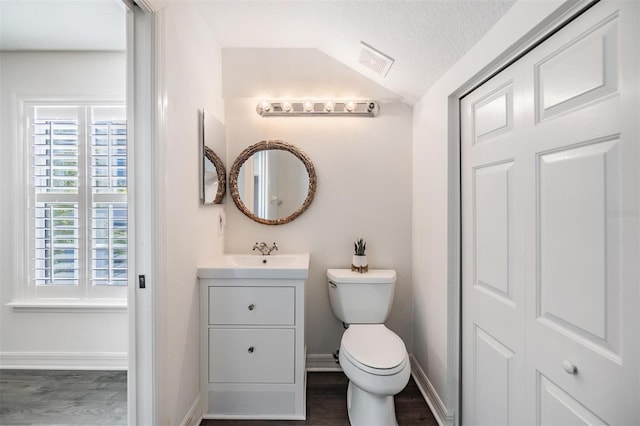 bathroom featuring wood-type flooring, vanity, a textured ceiling, and toilet