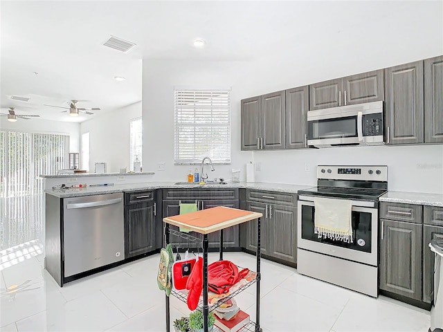 kitchen featuring sink, light tile patterned floors, gray cabinets, stainless steel appliances, and kitchen peninsula