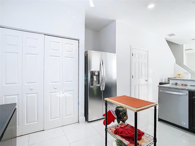 kitchen with appliances with stainless steel finishes, stone countertops, and light tile patterned floors