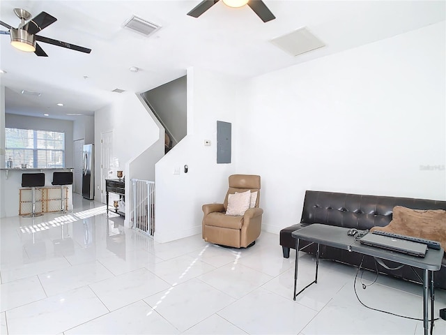 living area with light tile patterned flooring, electric panel, and ceiling fan