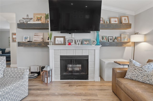 living room with a fireplace, crown molding, and light hardwood / wood-style flooring