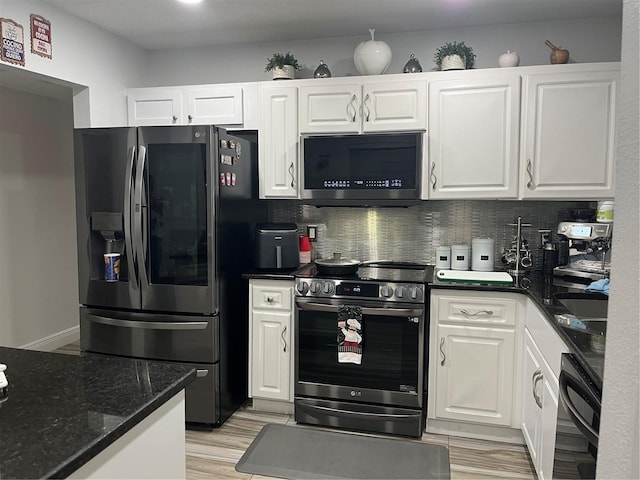 kitchen with white cabinetry, appliances with stainless steel finishes, decorative backsplash, and dark stone counters